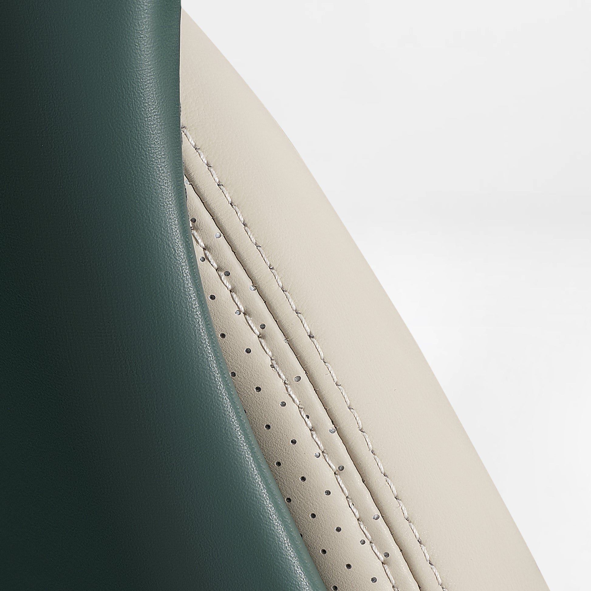 Eureka Ergonomic Serene executive chair side detail: forest green smooth leather meets cream perforated leather with contrast stitching.