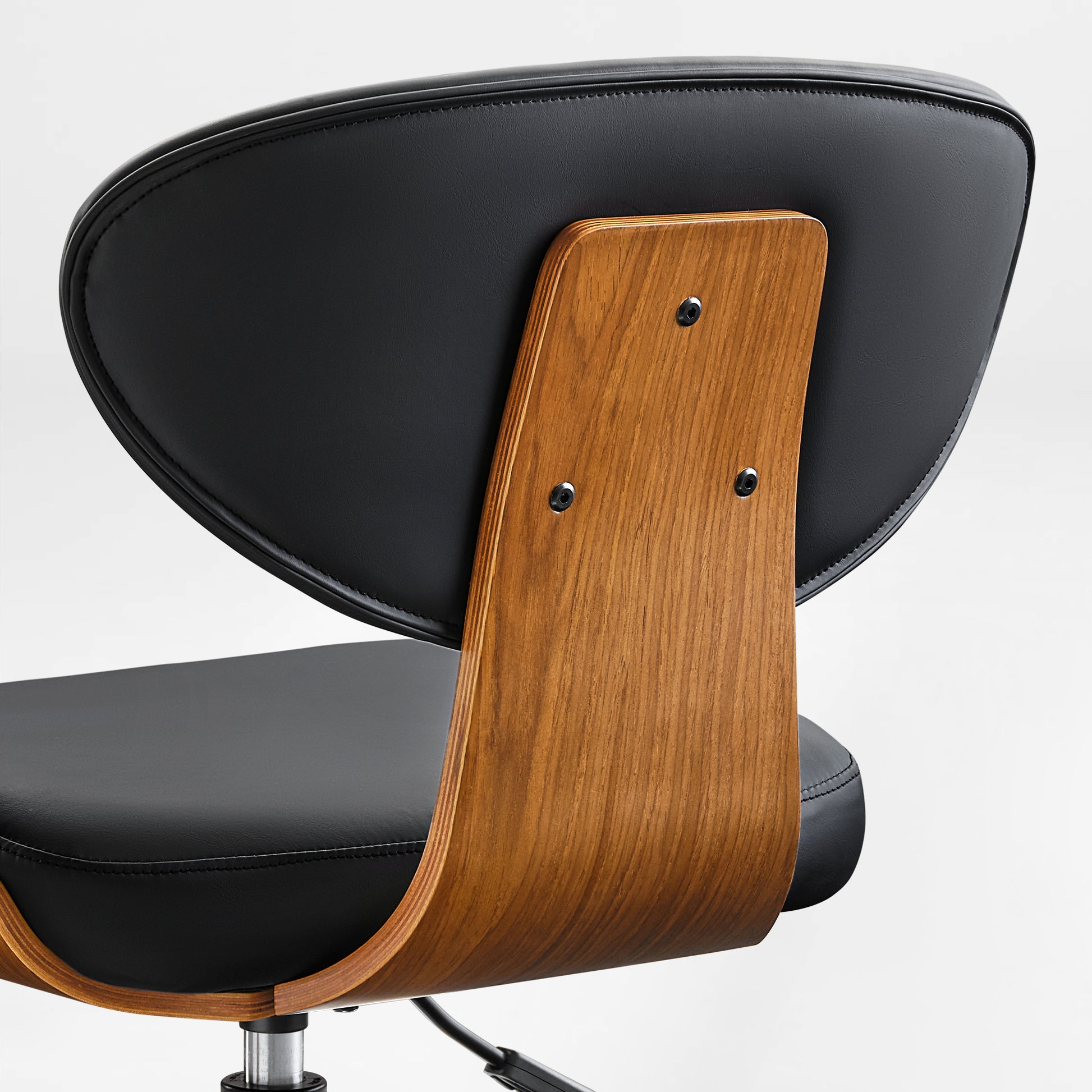 Eureka Ergonomic Matt black faux leather chair with curved walnut veneer shell, showcasing stitching and wood grain detail.