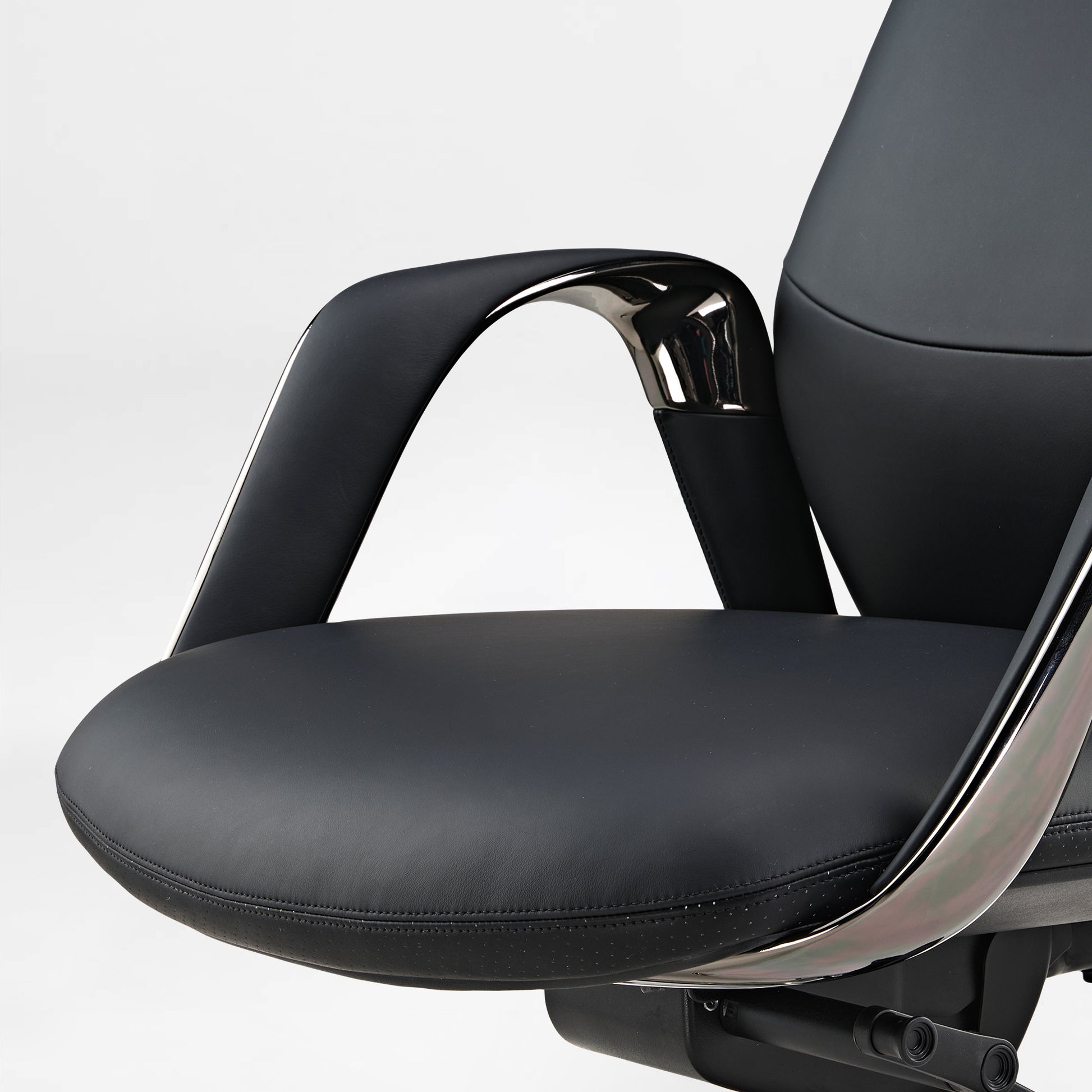 Eureka Ergonomic Serene black Napa leather executive chair armrest and perforated seat detail with chrome accents.