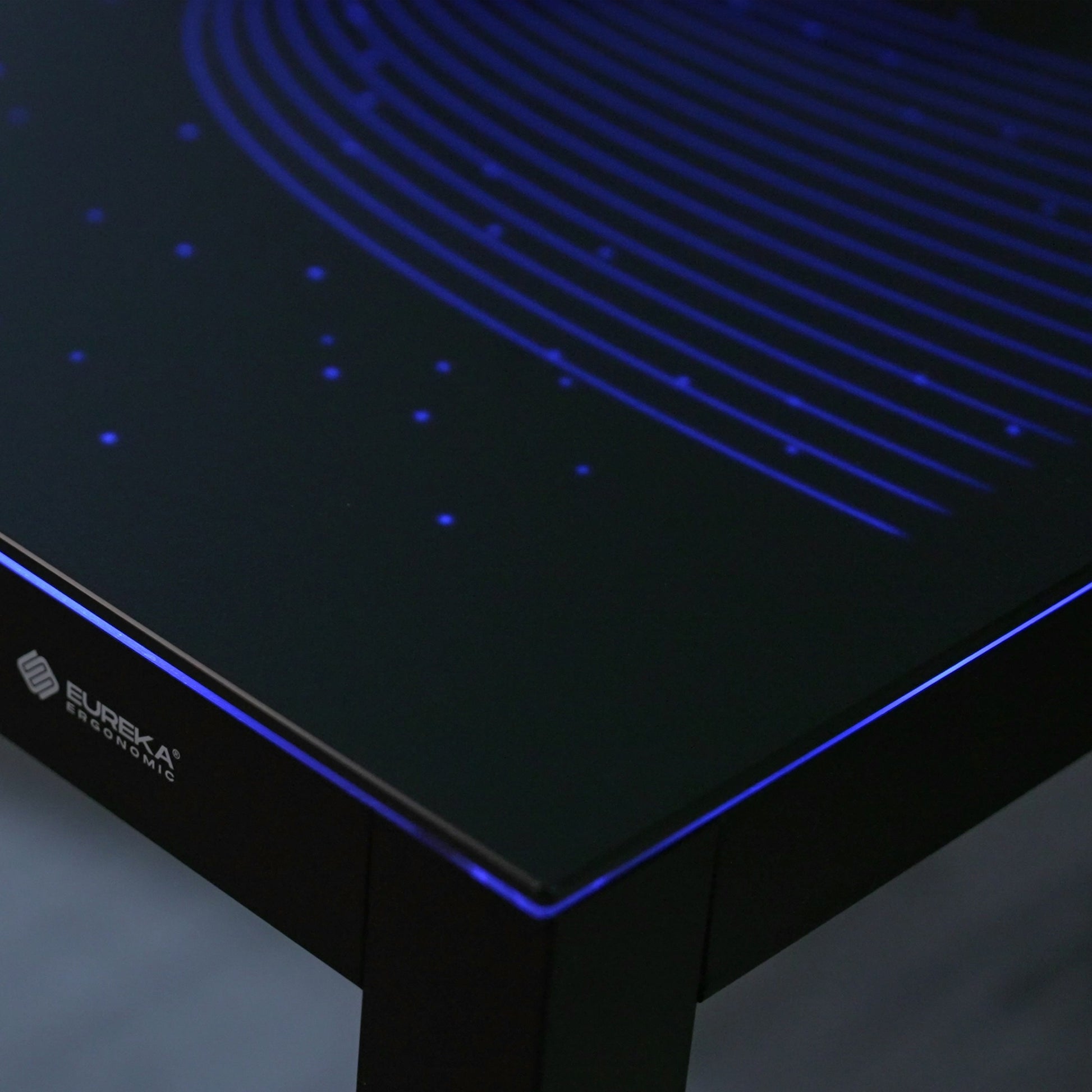 Eureka Ergonomic GTG L-shaped gaming desk with blue wave RGB lighting on tempered glass.