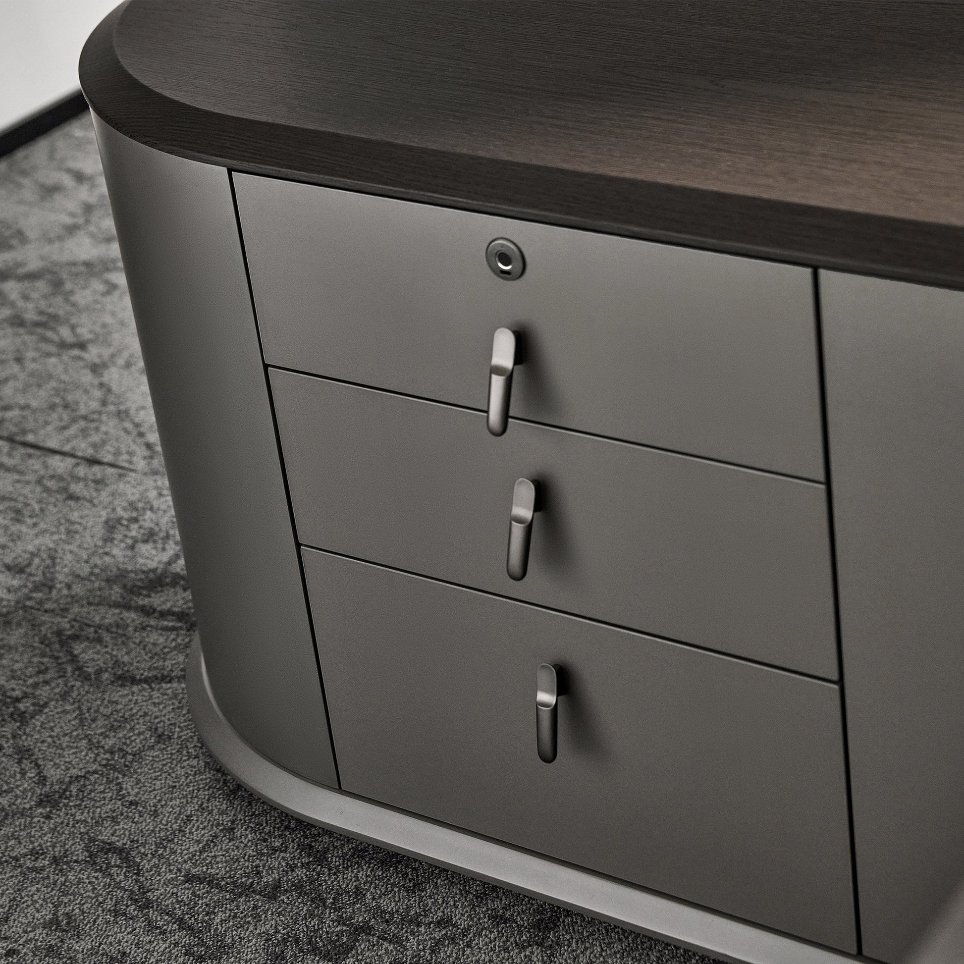 Eureka Ergonomic Zen Orion executive desk detail: dark wood grain top and dark gray drawers with metallic handles and keyhole.