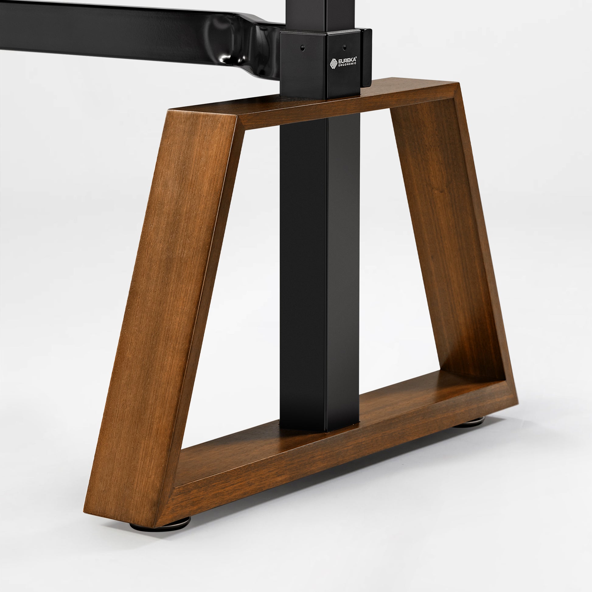 Eureka Ergonomic Ark Pro Standing Desk Base: Walnut Trapezoidal Legs, Black Carbon Steel Frame, and Solid Wood Construction.