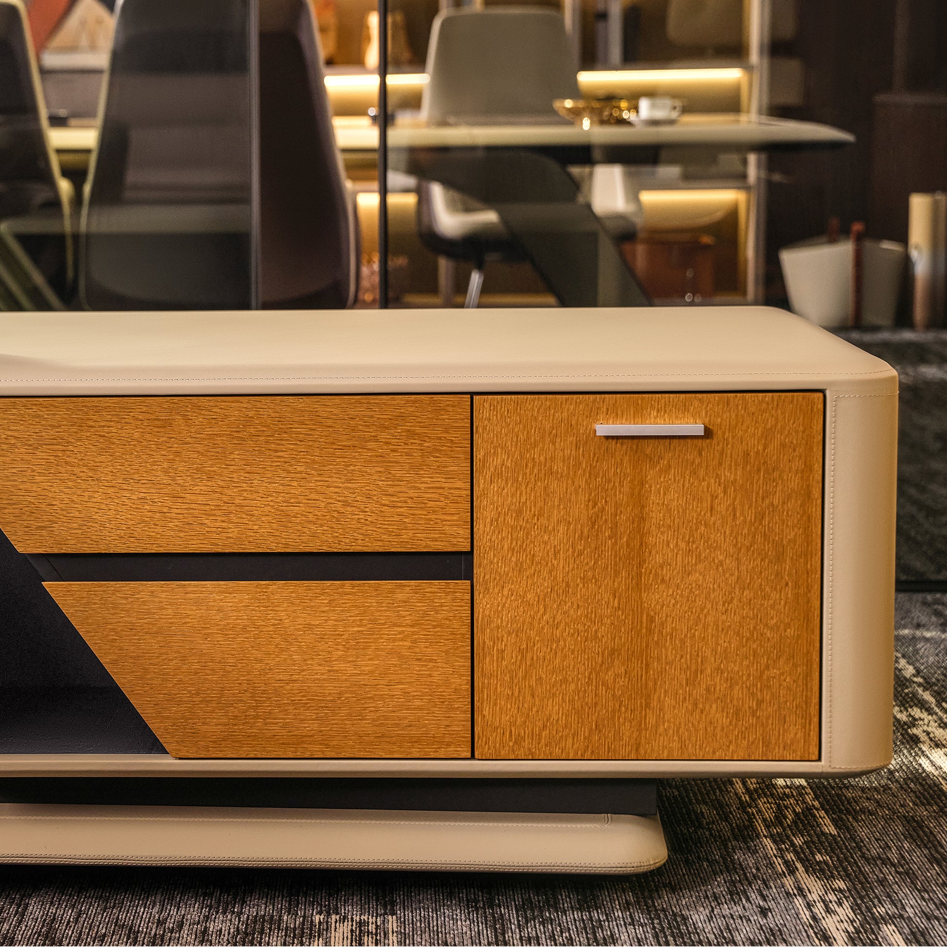 Eureka Ergonomic Zen Lunar executive desk close-up: warm wood grain drawers, brushed metal handle, beige leatherette trim.