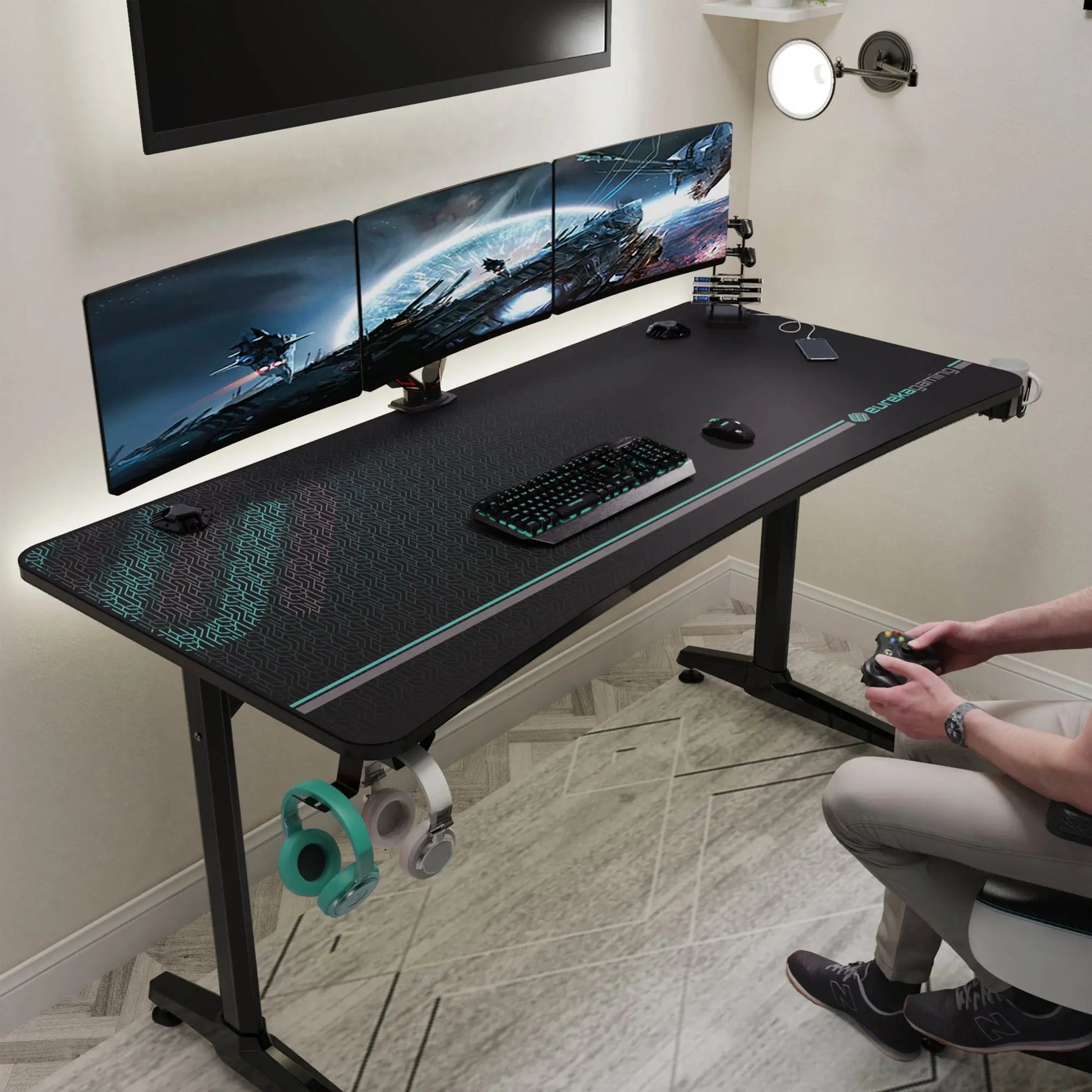 Eureka Ergonomic Gip 60 Gaming Desk With Full-Surface Mousepad, Accessories, and a Gamer Using a Controller.