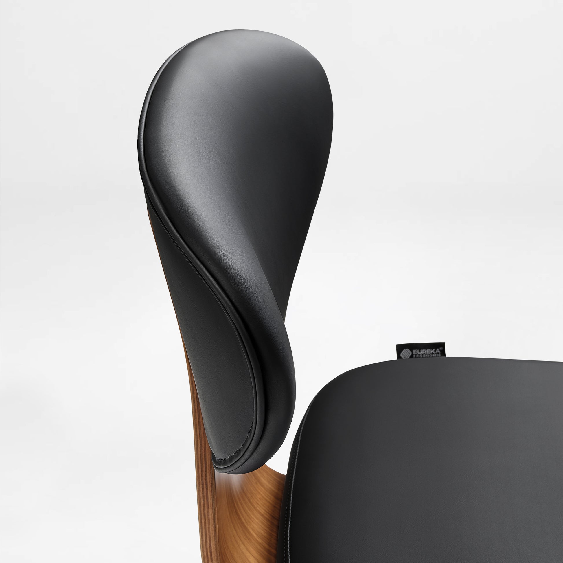 Eureka Ergonomic Matt black faux leather office chair backrest and seat detail with curved walnut veneer shell and visible stitching.