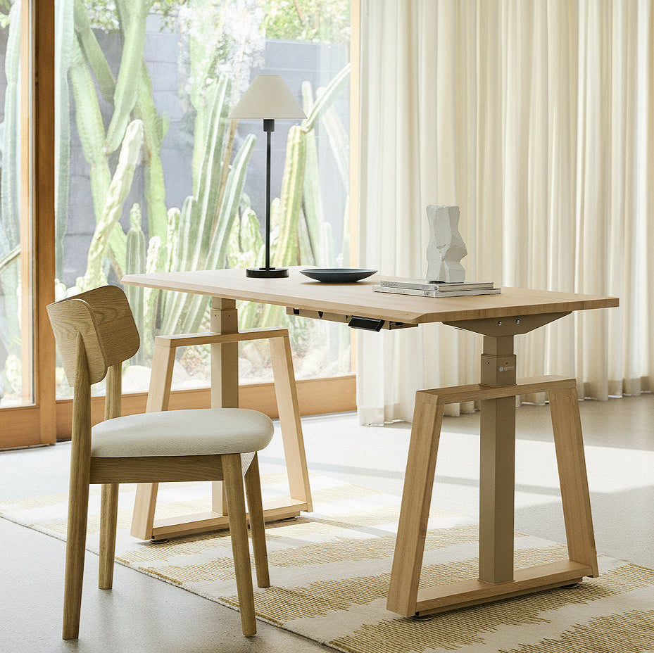 Eureka Ergonomic Ark Lite Standing Desk in light woodgrain finish with trapezoidal legs in a modern home office setting.