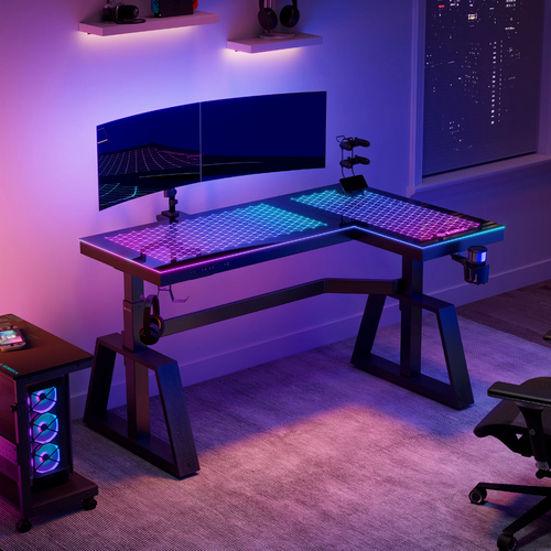 An L-shaped gaming desk with colorful LED lighting in a dark room at night.