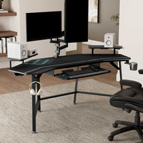 Eureka Ergonomic Black wing-shaped desk with dual monitors, speakers, keyboard, mouse, headphones, and cup holder for a gaming setup.