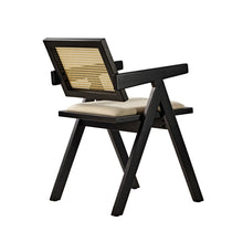 Eureka Ergonomic Mila black dining chair with woven rattan back, cream seat cushion, and splayed legs, side-rear view.