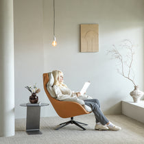 Woman Reading in Orange Ergonomic Chair With Rustic Vase Decor.