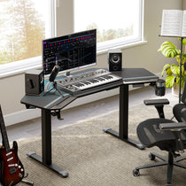 Eureka Ergonomic Aero Pro 63" black wing-shaped standing desk setup for studio use with monitor, speakers, keyboard, mic, guitar, and chair.