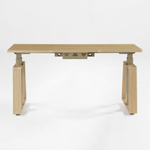 Eureka Ergonomic Ark Lite standing desk with light woodgrain MDF top, beige trapezoidal legs, and integrated cable management tray.