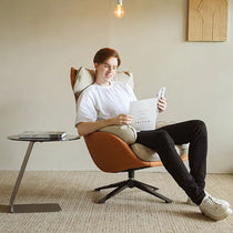 Man Reading in Todd Swivel Armchair With High Back, Orange Fabric and Cream Upholstery, Ergonomic Design.