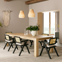 Eureka Ergonomic Four black Mila dining chairs with rattan backs and cream cushions around a light oak table in a dining room.