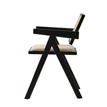 Eureka Ergonomic Black Mila dining chair, side profile view, showing handwoven rattan back, cream seat cushion, and splayed V-legs.