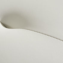 Close-Up of Aspen Upholstered Dining Chair Off-White Leather Detail, Textured Surface and Stitched Seam.