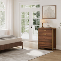 Modern Walnut 5-Drawer Chest Dresser With Gold Frame and Pulls in a Bedroom.