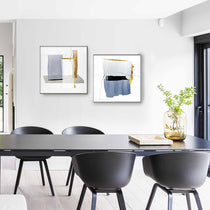 Set of 2 Abstract Wall Art Prints in Blue, Gold, and Gray Geometric Designs Above Dining Table.