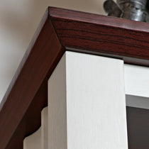 Eureka Ergonomic Close-up of the top corner of a white bookshelf with dark cherry wood trim. Product appearance detail.