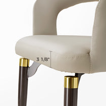 Chantilly Dining Chair Detail With Cream Faux Leather, Gold Accents, and Brown Legs; 3 1/8 Inch Measurement.