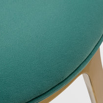 Katalea Green Velvet Dining Chair Close-Up. Emerald Green Velvet Upholstery and Wooden Leg Detail.