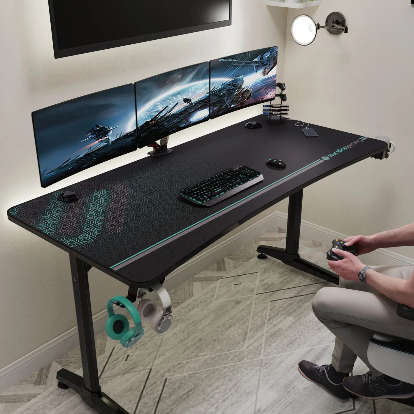 Eureka Ergonomic Gip 60 Gaming Desk With Full-Surface Mousepad, Accessories, and a Gamer Using a Controller.