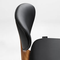 Eureka Ergonomic Matt black faux leather office chair backrest and seat detail with curved walnut veneer shell and visible stitching.