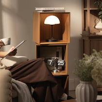 Eureka Ergonomic Cubo walnut rotating storage cabinet as a side table beside a person reading on a sofa at home