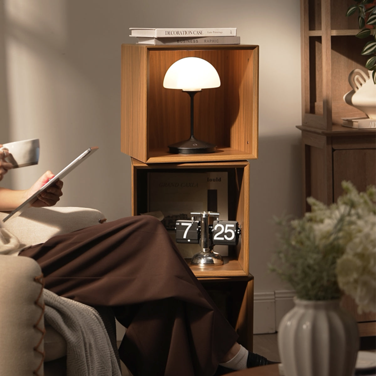 Eureka Ergonomic Cubo walnut rotating storage cabinet as a side table beside a person reading on a sofa at home