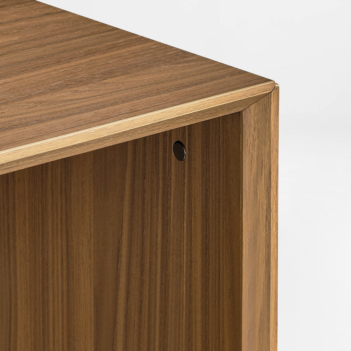 Eureka Ergonomic Cubo walnut cube top corner close-up showing the beveled edge and the refined metal screw cap covering the fastener.