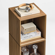 Eureka Ergonomic Cubo walnut cube styled with over-ear headphones, a book and a portable speaker on top
