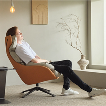 Todd Swivel Armchair in Orange With Cream Headrest, a Person Relaxing in the Chair. Ergonomic Design.