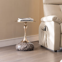 15 Round Metal Top Side Table With Marble Base and Gold Stem, Next to Cream Leather Recliner.